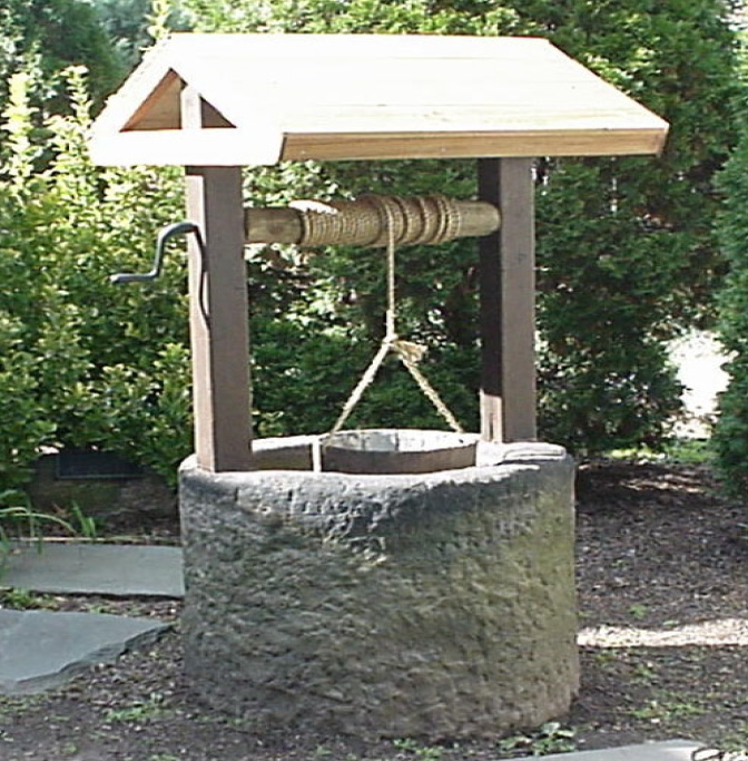 Historic well-house with windlass, rope, and bucket illustrating how households drew drinking water before indoor plumbing
