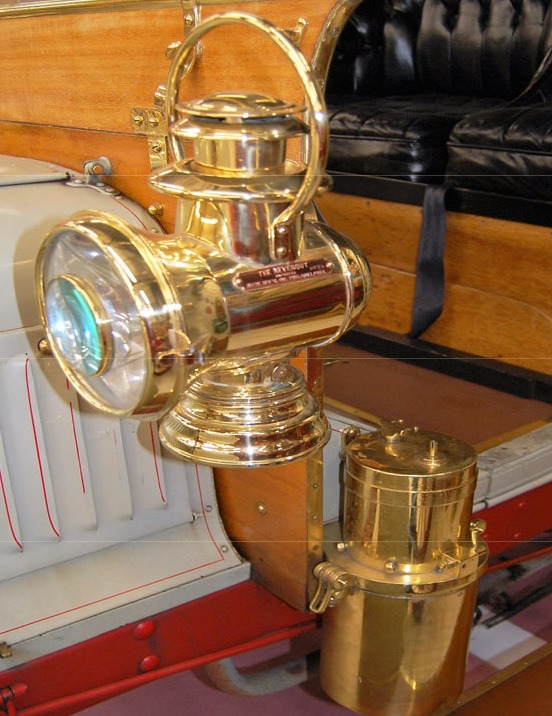 Polished brass Prest-o-lite gas-fired headlight and side lamp on an early automobile.