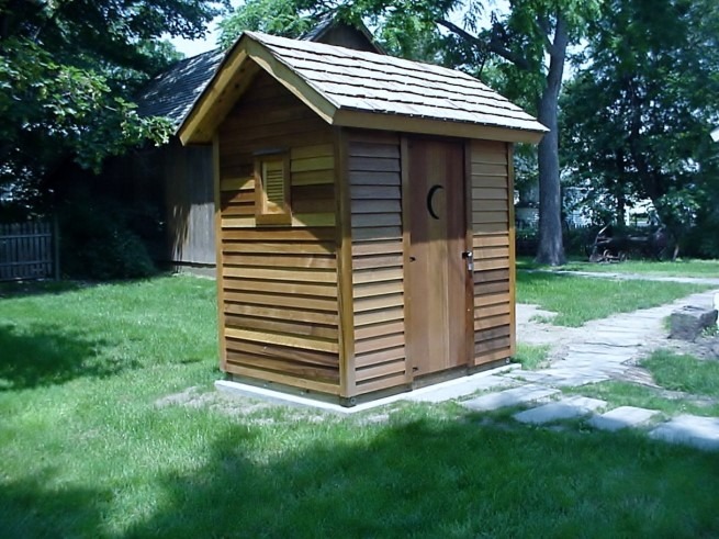Wooden two-hole privy outhouse with crescent-moon door on the grounds of Liberty Hall Museum.