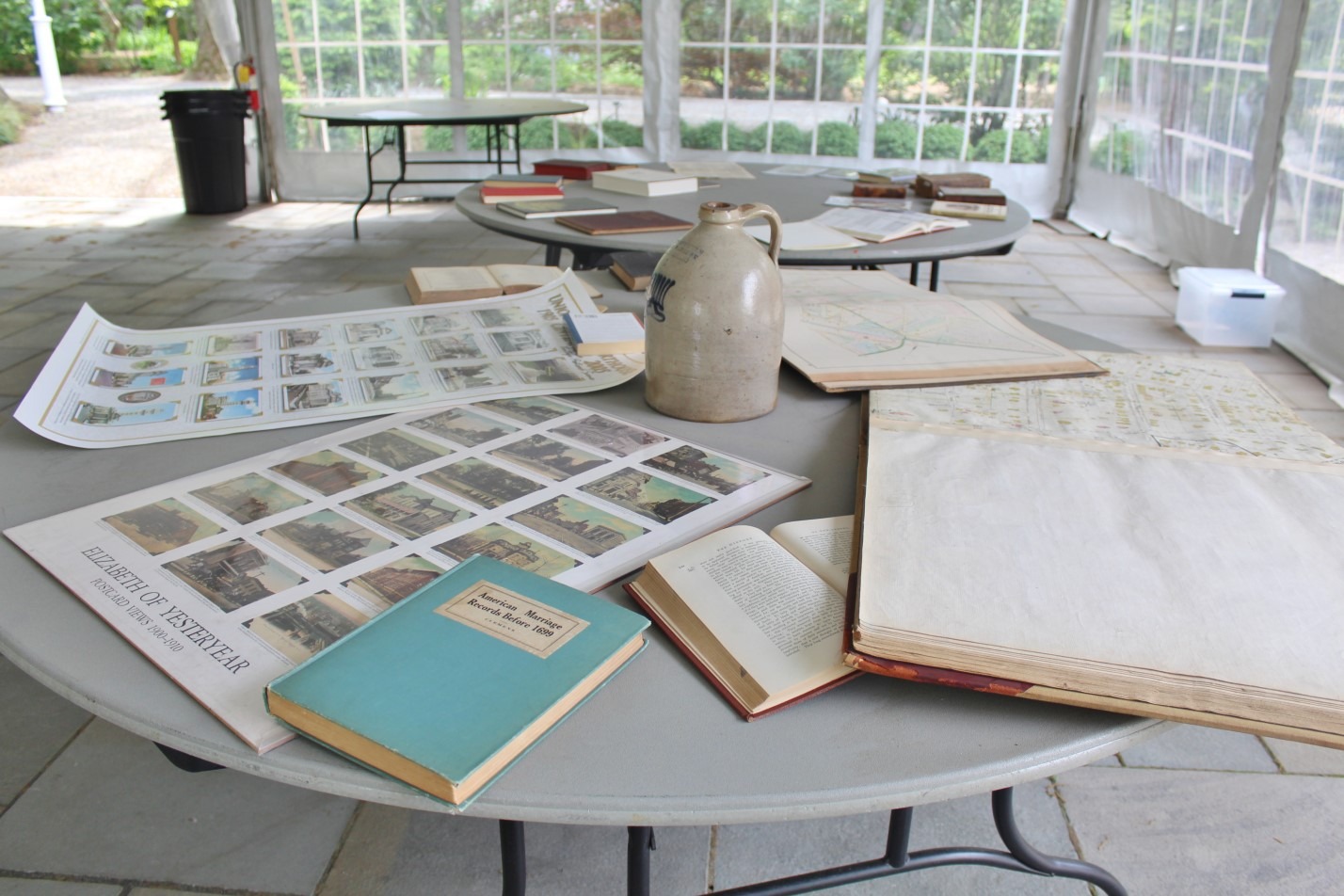 Table displaying historical artifacts including old maps, record books, and a clay jug from Elizabeth pottery works