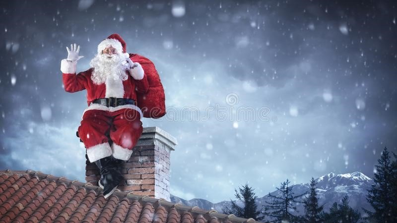 Santa Claus sitting on a brick chimney with a toy sack during a snowy winter night