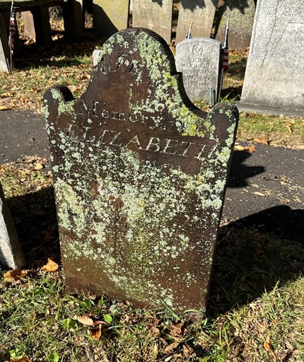 Lichen-covered gravestone before cleaning with “In Memory of Elizabeth” visible.