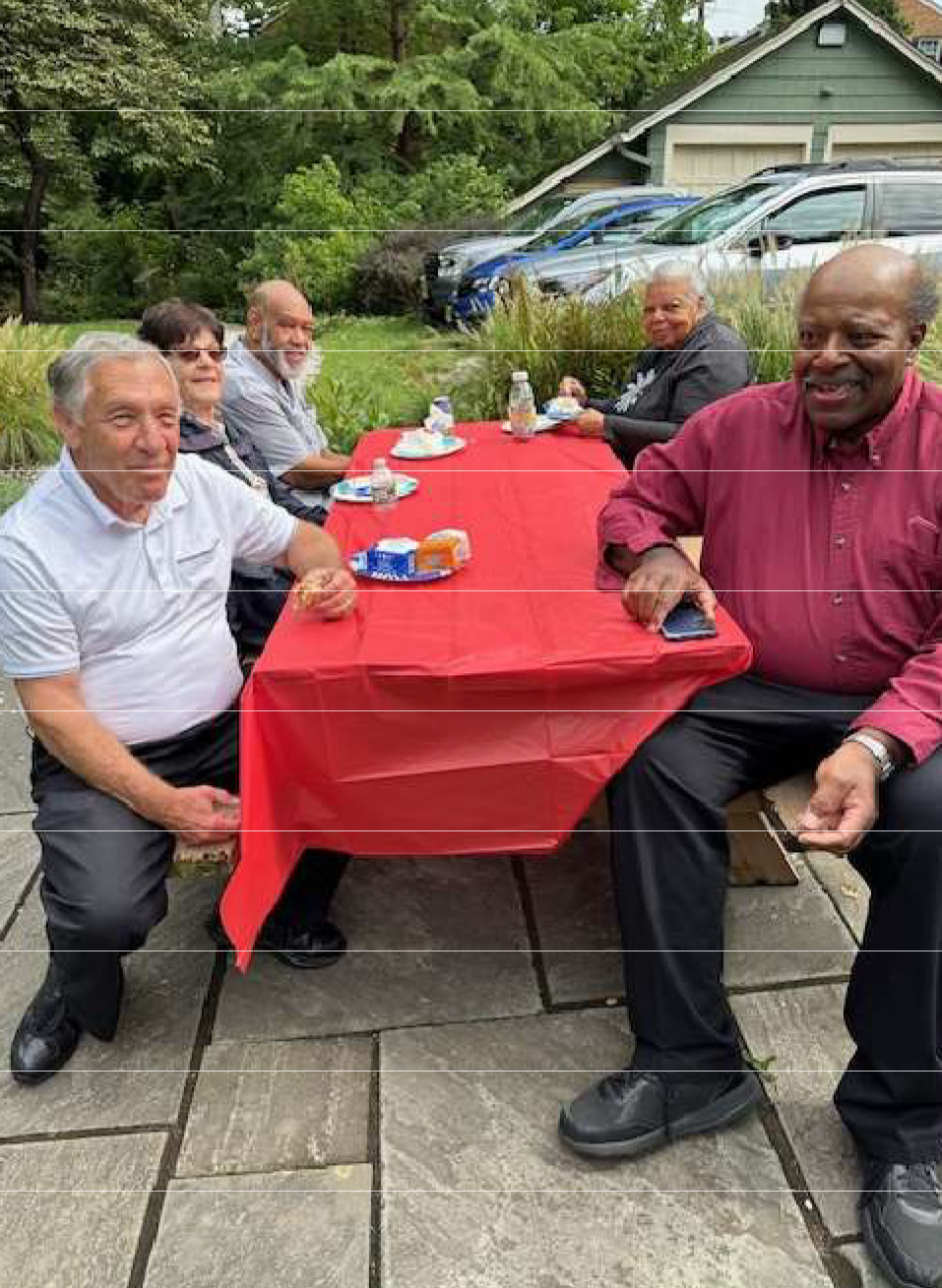 Members gathered around a picnic table with a red tablecloth at the UCHS annual picnic