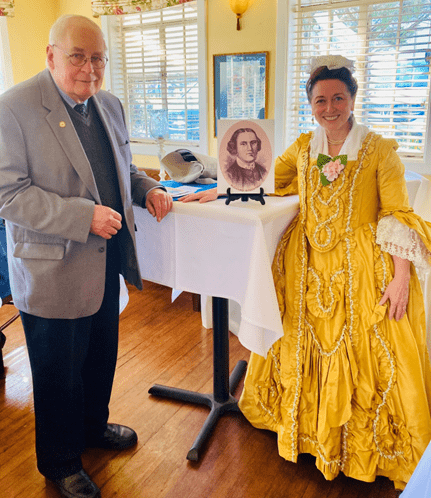 Alisa Dupuy portraying Annis Boudinot Stockton beside a portrait display at the 2026 Union County Historical Society annual luncheon.